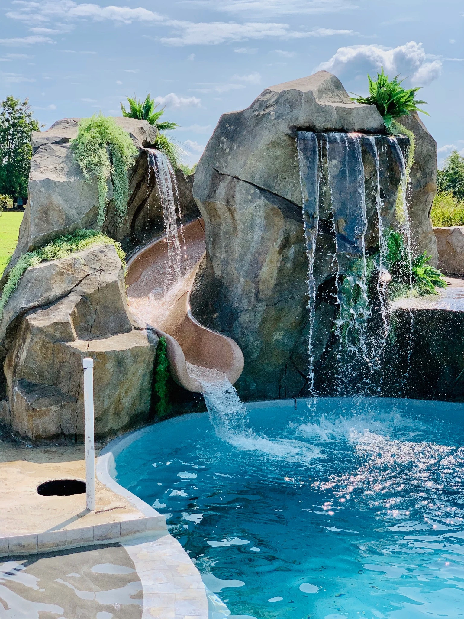 Curved waterslide between hand-sculpted rocks and flowing waterfalls